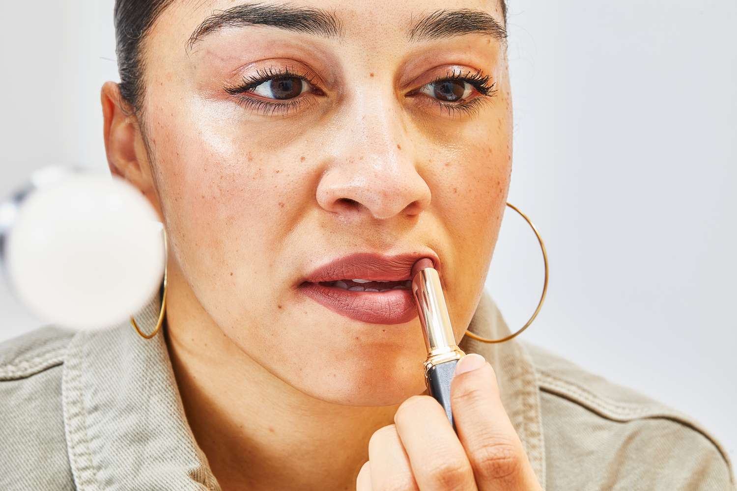 A person applying the L'Oréal Colour Riche Intense Volume Matte Lipstick on their lips