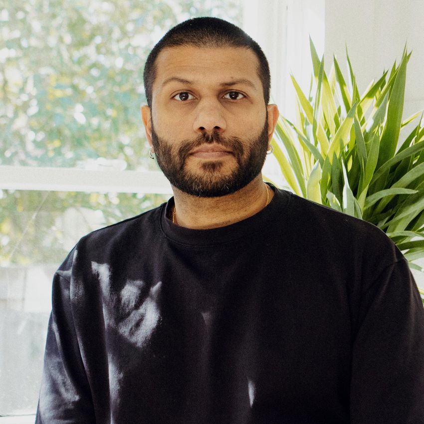 Dhiran Mistry posing with black shirt in front of window