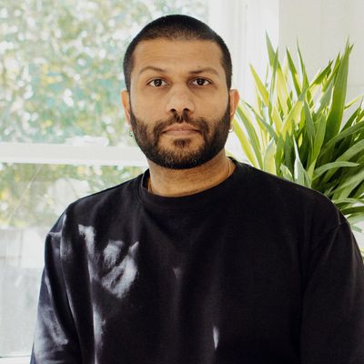 Dhiran Mistry posing with black shirt in front of window