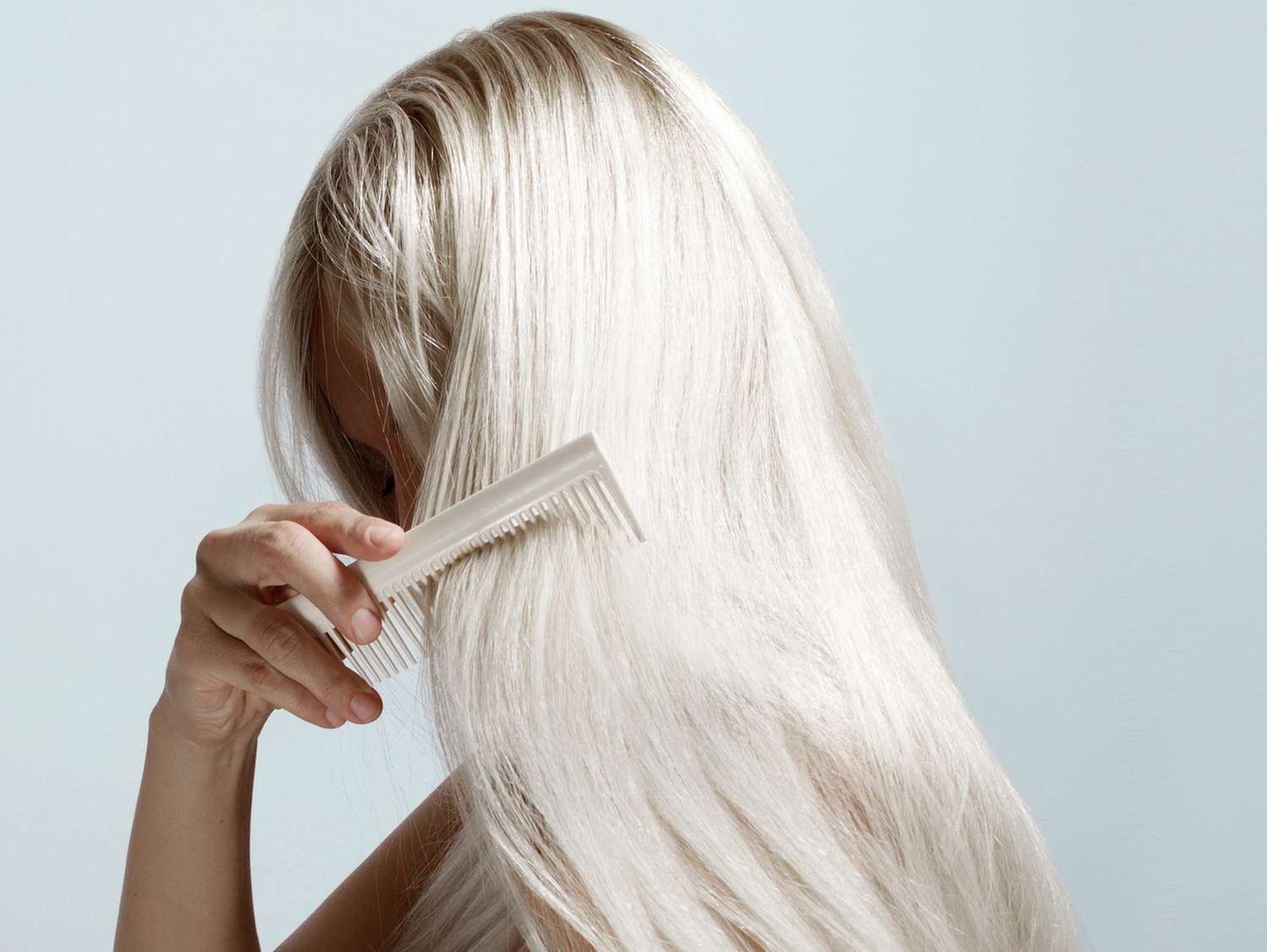 woman combing through long platinum blonde hair