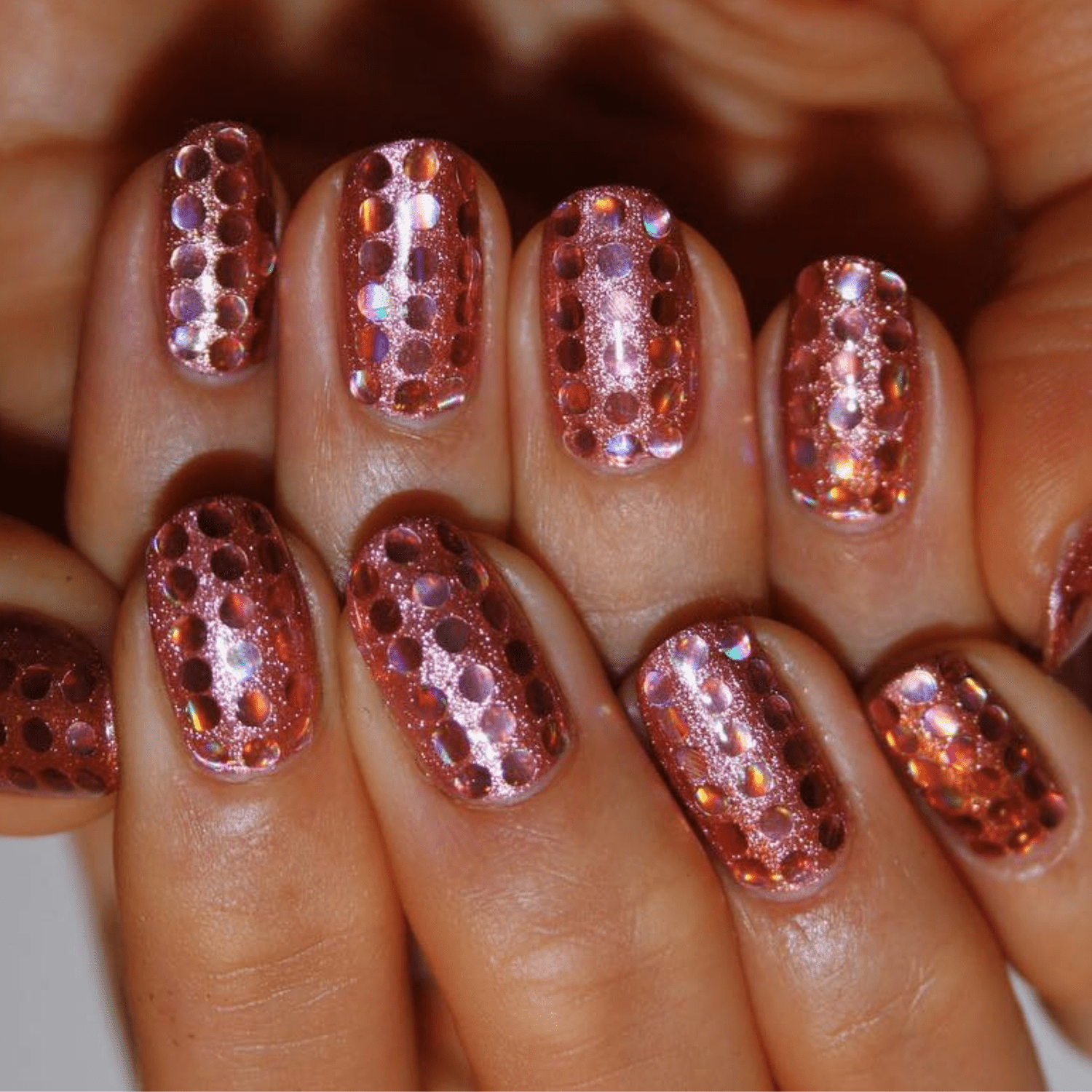 Rose gold glitter nails with metallic dot sequins.